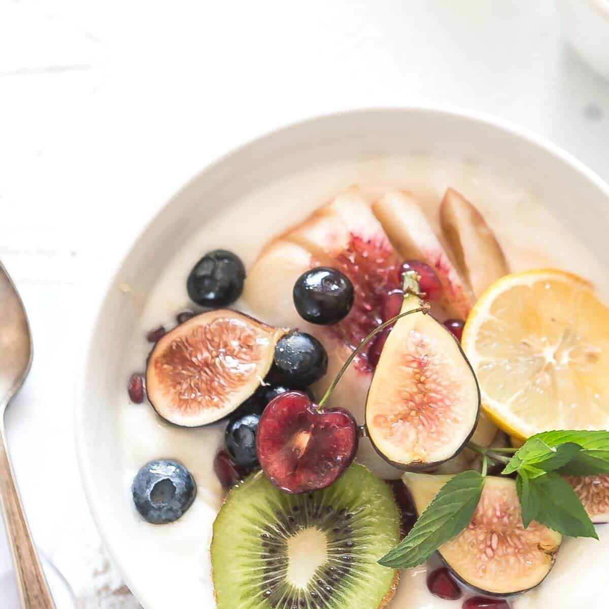 A bowl of yogurt topped with an assortment of sliced fresh fruit. 