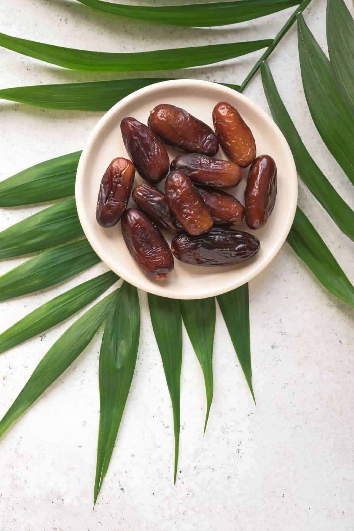 A small plate of fresh dates placed over a palm leaf.