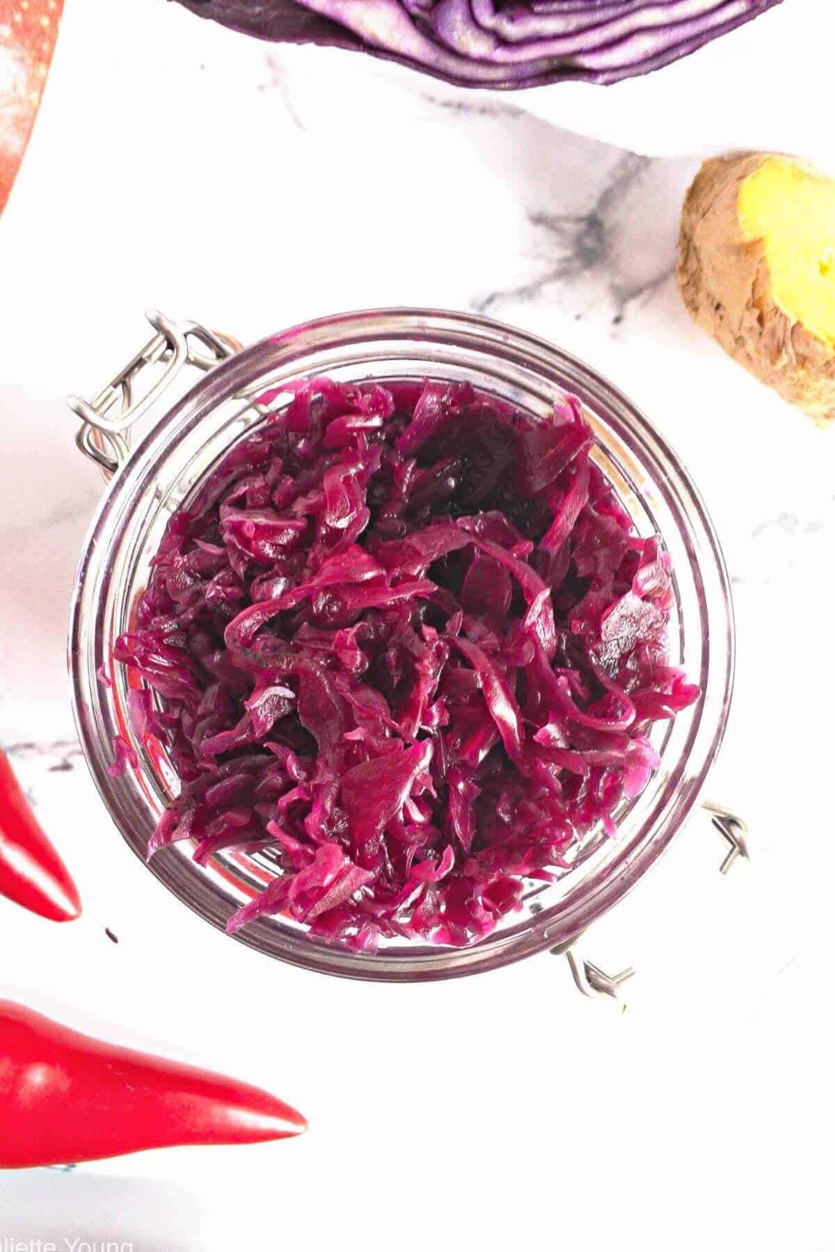 Top down view of a jar of red cabbage sauerkraut and red chillies.