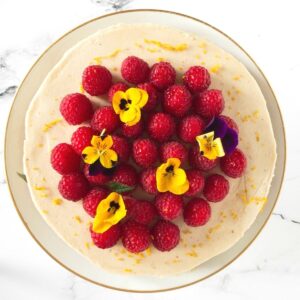 A vanilla cheesecake topped with fresh raspberries and edible flowers.