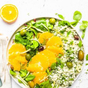 Cauliflower couscous with a green salad and slices of orange.