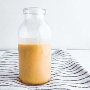A small glass bottle filled with tahini salad dressing.