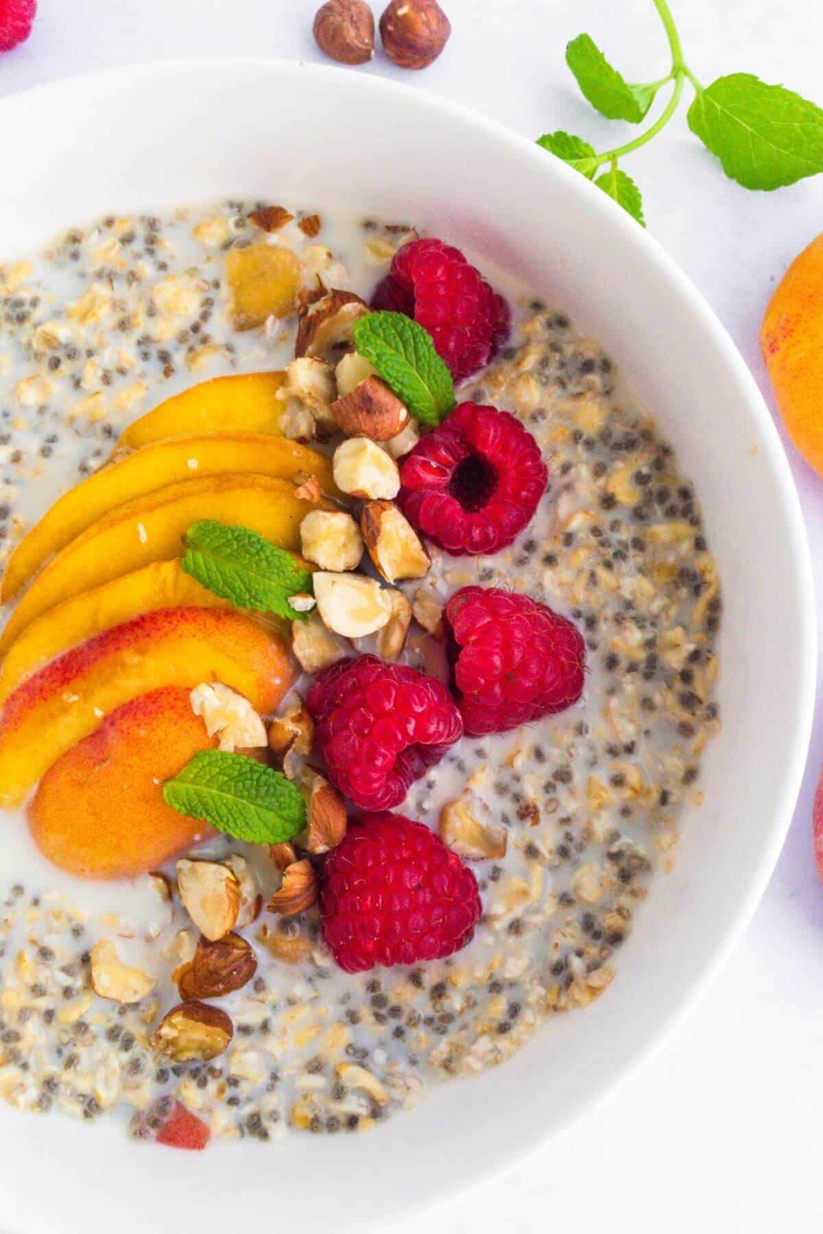 Peach and raspberry breakfast cereal with chopped hazelnuts and fresh mint.