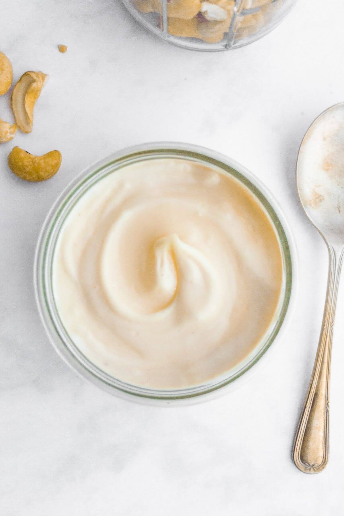Cashew mayonnaise in a small jar next to a spoon.
