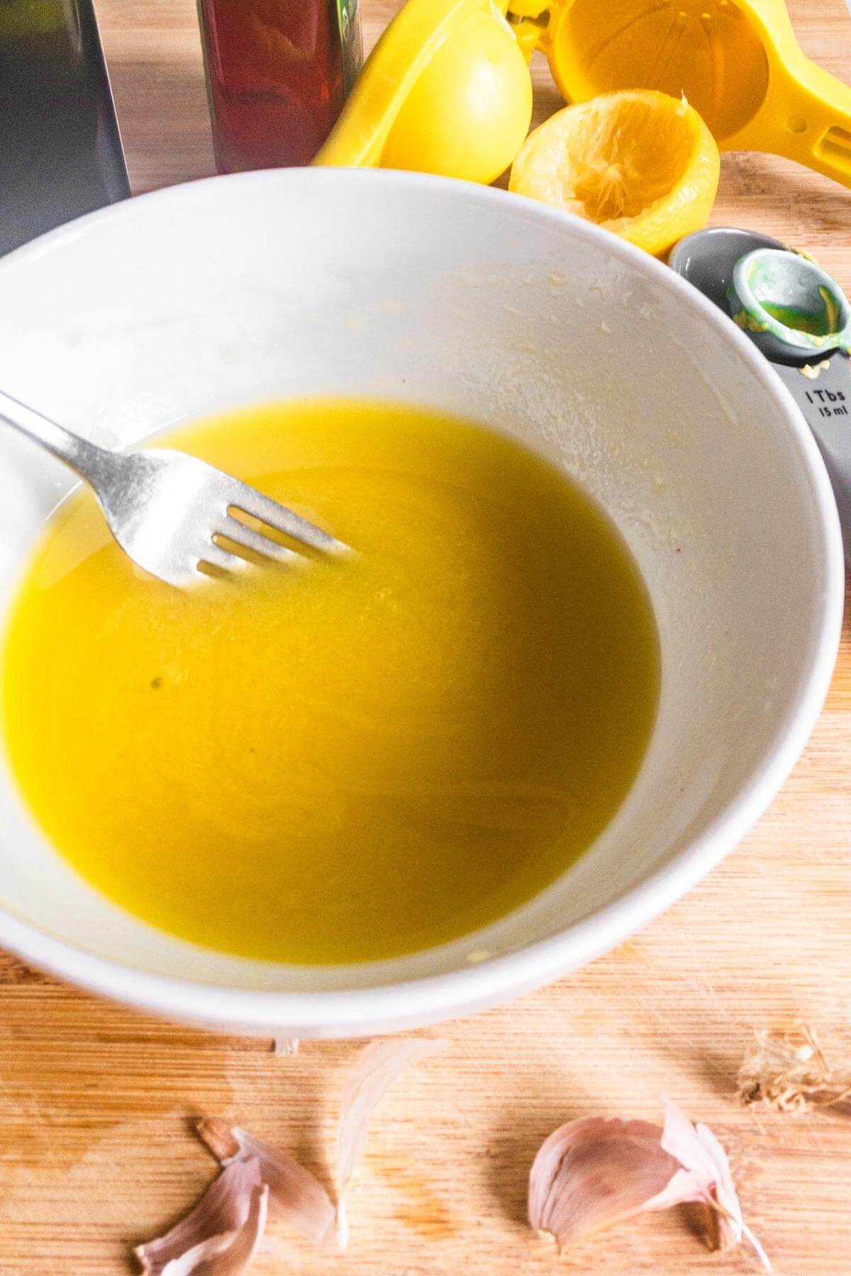 A salad dressing is being whisked up with a fork in a small bowl.