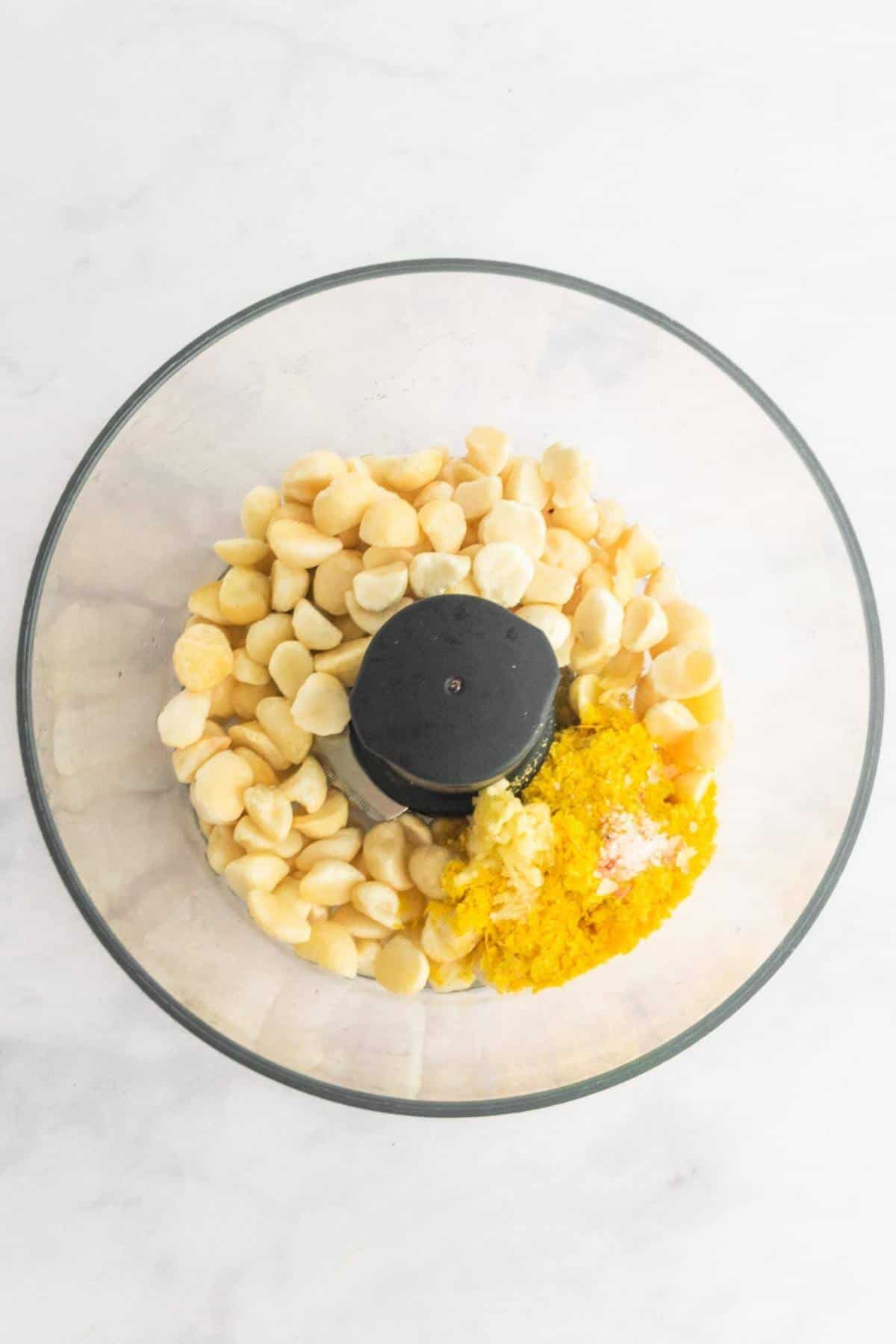 Macadamia cheese recipe ingredients added to a food processor.