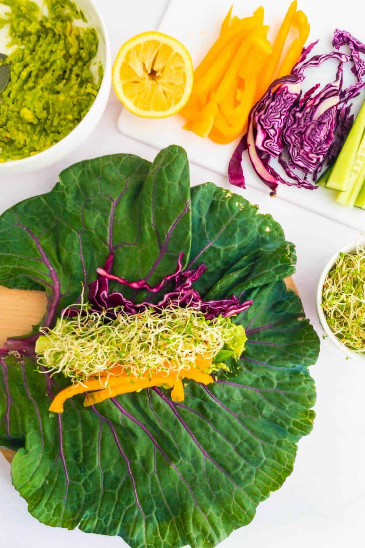 A large kale leaf topped with sliced vegetables and sprouts.