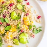 A plate of sprouted quinoa salad next to a glass with vinaigrette.