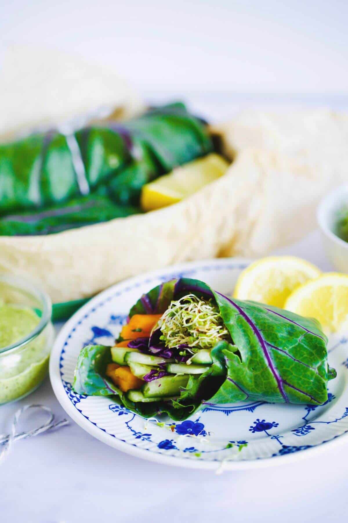 A halved collard wrap on a small blue and white plate with dressing on the side.