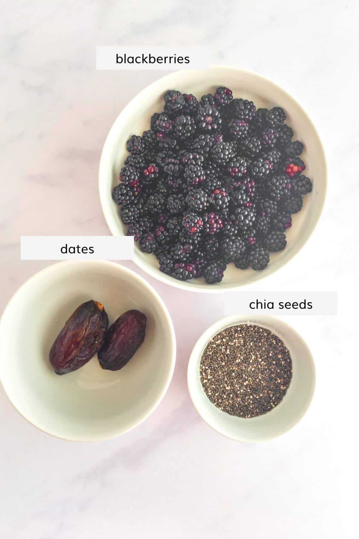 A bowl of blackberries, a bowl with chia seeds and a bowl containing two dates sit on a marble work surface. They ingredients are labelled.