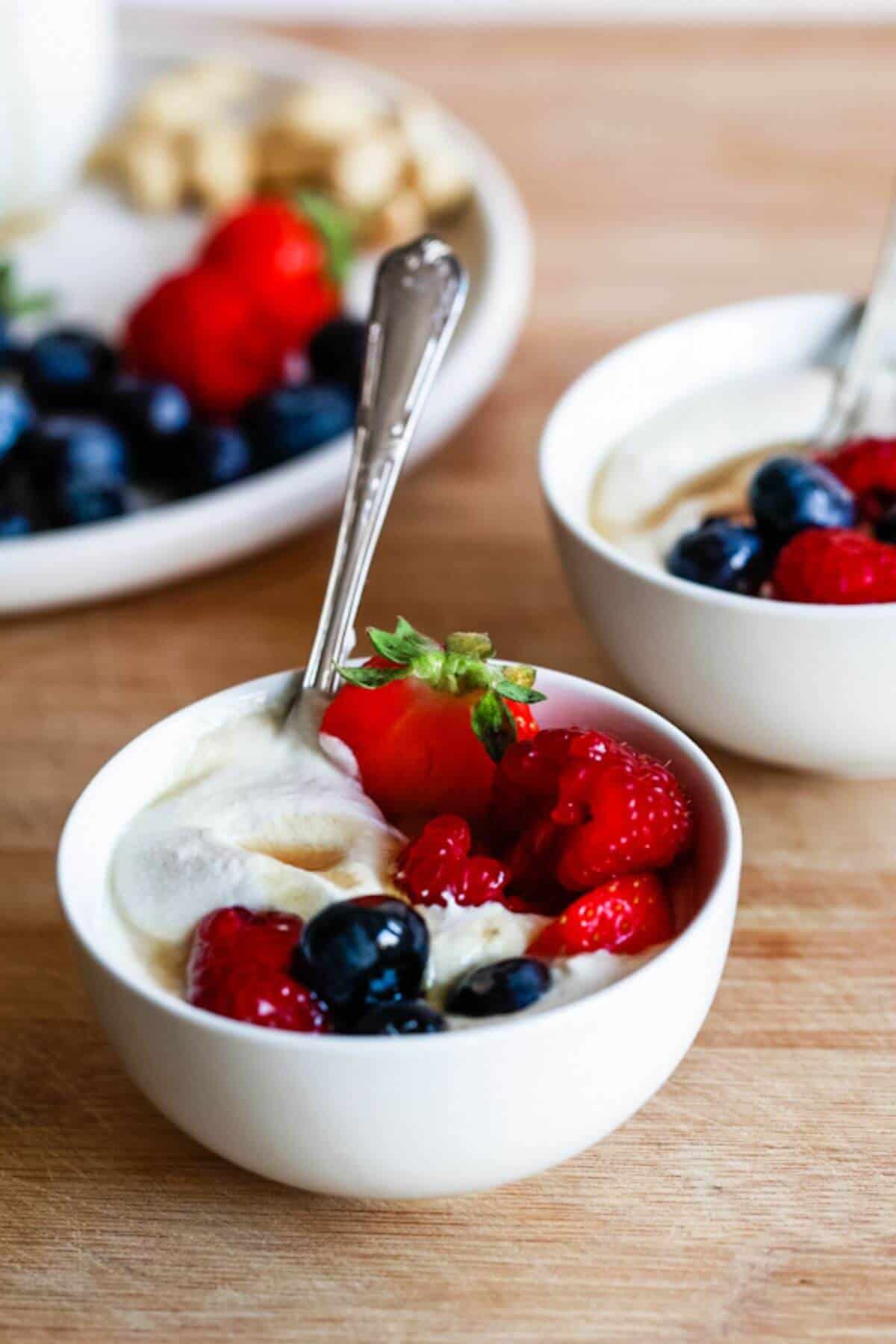 Two small bowls filled with yogurt and mixed berries.