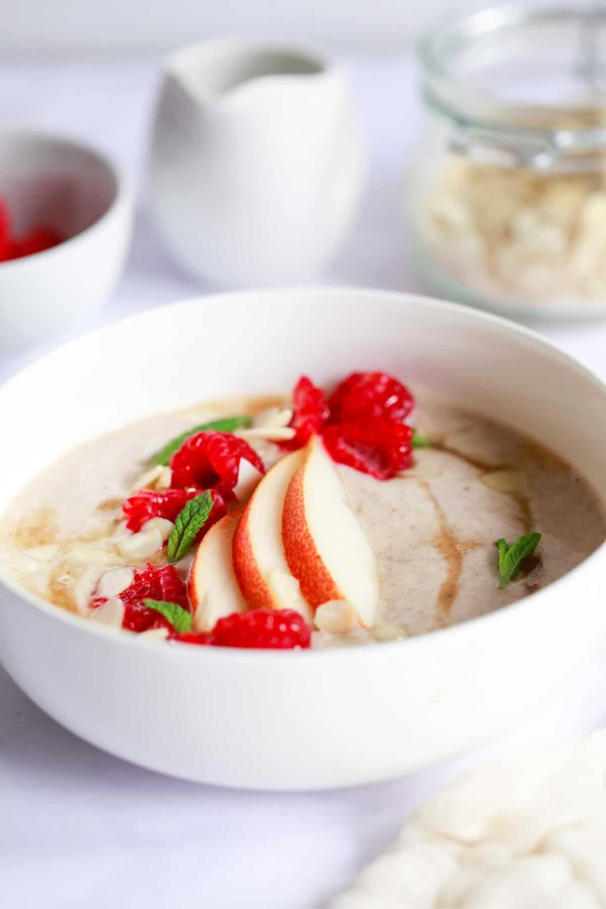 A bowl of porridge topped with pear and raspberries.