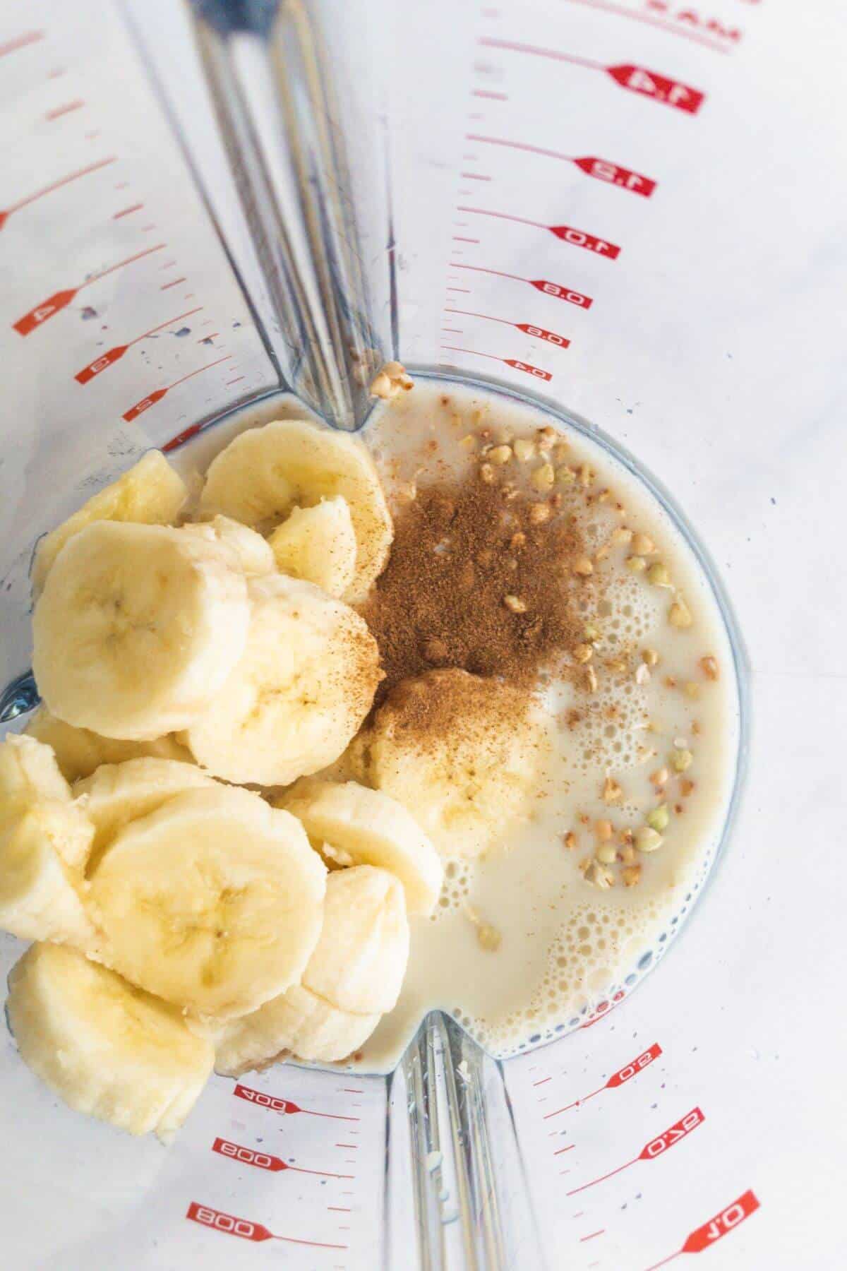 Banana, powdered cinnamon, buckwheat groats and milk sitting in a blender.