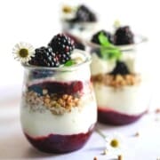 3 small parfaits in dessert glasses filled with buckwheat, jam and topped with fresh blackberries.