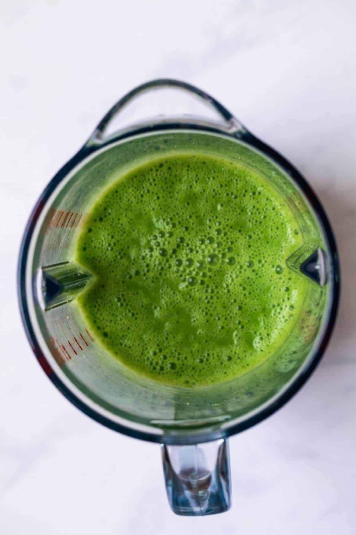 Bright green and bubbly, freshly blended green smoothie sitting in the blender.