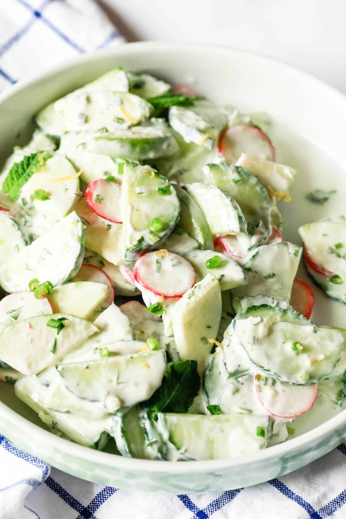 A bowl of cucumber salad in a yogurt and herb dressing.