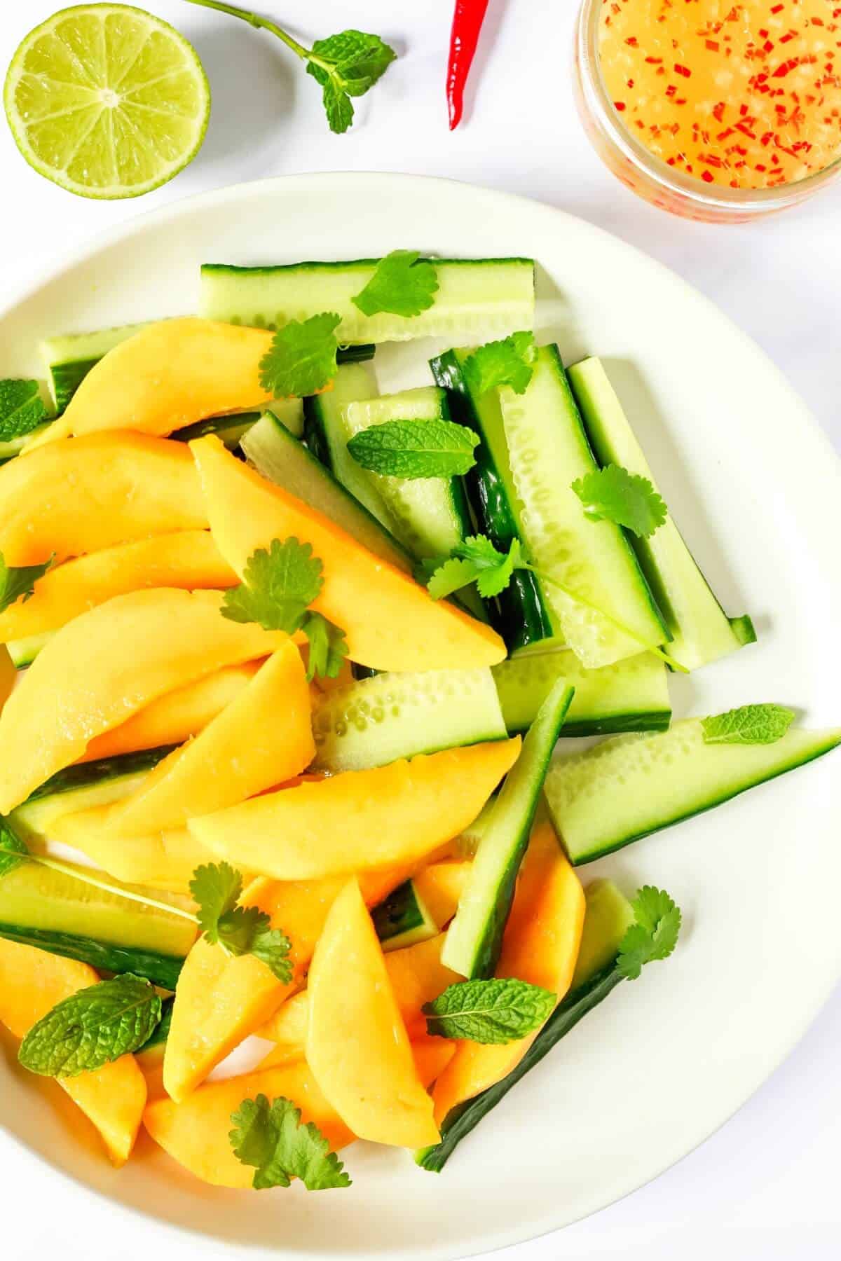 Slices of mango and cucumber sprinkled with fresh herbs; a chopped chilli based dressing on the side.